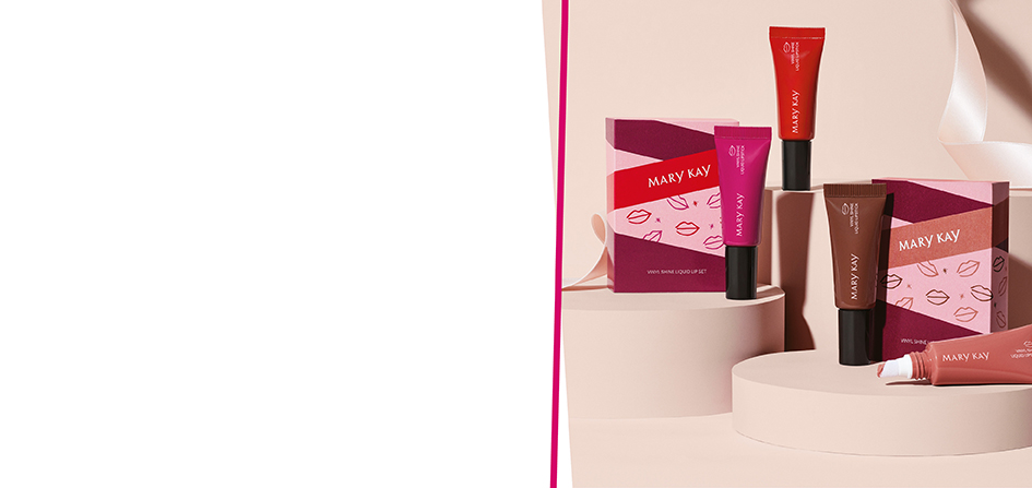 De Mary Kay Vinyl Shine Liquid Lips Set (alle vier kleuren: Luminous Red, Vivid Berry, Glowing Neutral en Brilliant Brown) staan op roze verhogingen naast de fraaie kerstverpakkingen