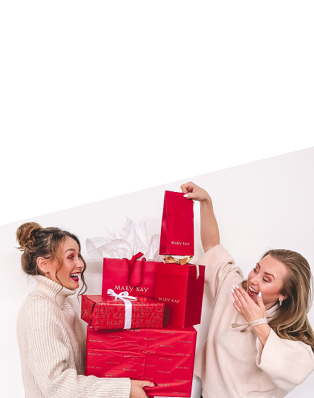 Twee zelfstandige schoonheidsconsultants met Mary Kay dragen en stapelen in rood cadeaupapier verpakte kerstcdeaus