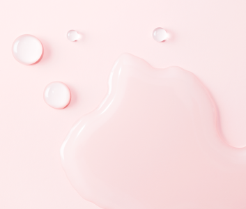 Voor een roze achtergrond zijn druppels van een huidverzorgingscrème te zien