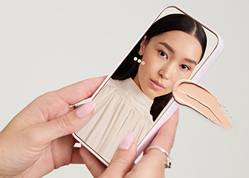 Vrouw houdt mobiele telefoon in haar hand en gebruikt de Foundation Matching Tool.