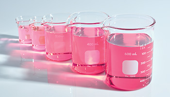 Vijf reageerbuisjes met roze vloeistof die hydraterend werkt
