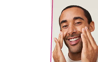 Een man glimlacht naar de camera terwijl hij met beide handen een huidverzorgingsproduct op zijn gezicht aanbrengt