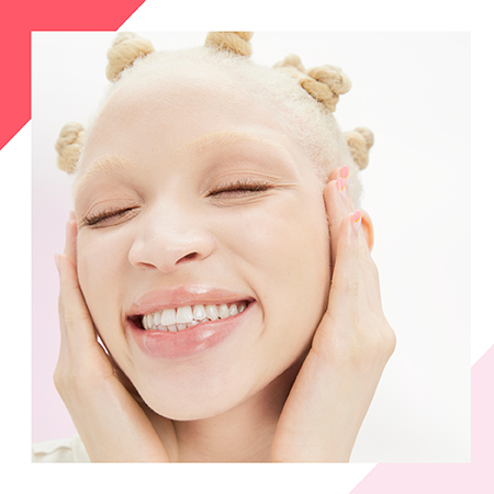 Een blonde jonge vrouw met bantoeknotjes in haar haar en een gezonde, lichte huid