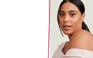 Een lachende vrouw met bruin haar, een stralende huid en gesloten ogen grijpt met één hand naar haar gezicht