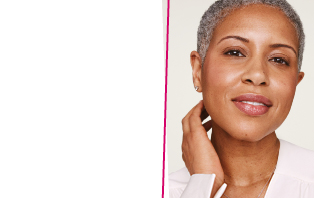 Een glimlachende vrouw met een stralende huid en grijs, kort haar pakt met één hand haar nek vast