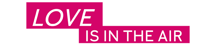 De tekst “LOVE IS IN THE AIR” in wit schrift voor een pinke achtergrond