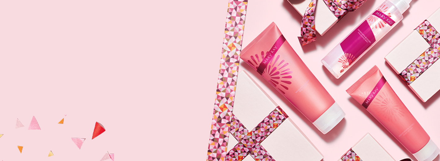 De Mary Kay Mandarin Blooms Body Care Set is genesteld tussen roze geschenkverpakkingen en lint