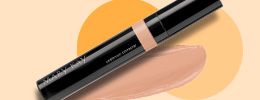 De Mary Kay® Undereye Corrector ligt naast een likje product op een beige achtergrond.