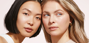 Close-up van de gezichten van twee jonge vrouwen (ongeveer 20 jaar oud) met verschillende huidskleur en haarkleur - beiden hebben een stralende, heldere huid