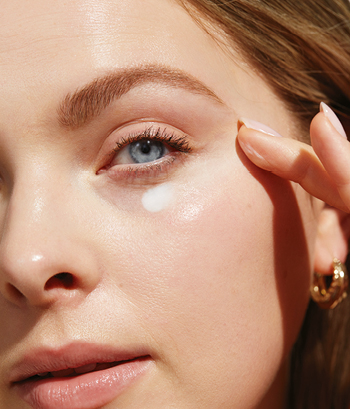 Close-up van het gezicht van een vrouw die Mary Kay oogcrème aanbrengt met haar vingers