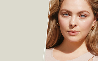 Een vrouw van begin 20 met een stralende, heldere huid lacht frontaal in de camera