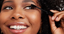 Een vrouw brengt Mary Kay Ultimate Mascara op haar wimpers aan en glimacht