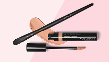 Een geopende tube Mary Kay Undereye Corrector is samen met de Mary Kay Cream Color Brush voor een tweekleurige roze achtergrond gefotografeerd