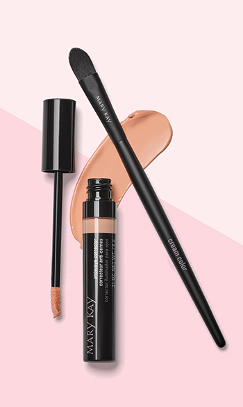 Een geopende tube Mary Kay Undereye Corrector is samen met de Mary Kay Cream Color Brush voor een tweekleurige roze achtergrond gefotografeerd