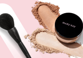 Een potje Mary Kay Silky Setting Powder, sporen van twee verschillende kleuren poeder alsmede de All-Over Powder Brush voor een roze-witte achtergrond
