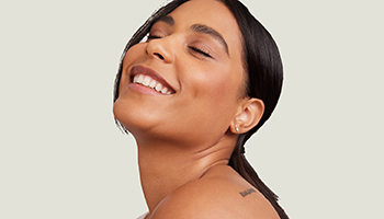 Een jonge vrouw met steil bruin haar die met lichtjes geopende mond en een knipoogje naar de camera kijkt