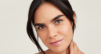 Een vrouw van middelbare leeftijd met kort haar en een stralend mooie huid glimlacht naar de camera