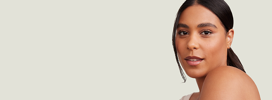 Een vrouw met sproeten en achterovergekamd, krullend haar glimlacht lichtjes en kijkt opzij