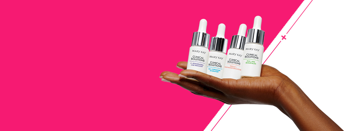 Een vrouwenhand houdt voor een pinke achtergrond de vier boosters van de Clinical Solutions huidverzorgingslijn omhoog.