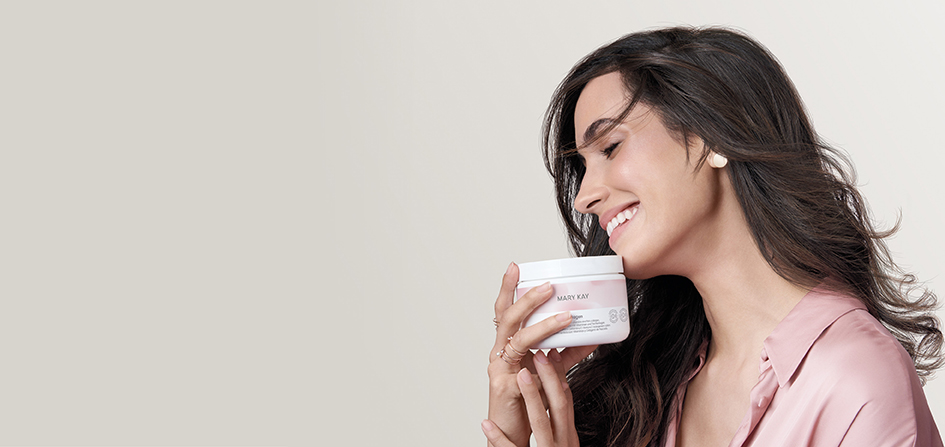 Een vrouw met lang bruin haar houdt een pot Mary Kay Collagen (collageenpoeder, voedingssupplement) in haar handen en glimlacht met gesloten ogen.