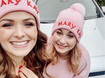 Twee stralende zelfstandige schoonheidsconsulentes met Mary Kay dragen roze Mary Kay mutsen