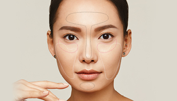 Een brunette vrouw kijkt frontaal in de camera. Afzonderlijke delen van haar gezicht worden met verschillende kleuren belicht - met behulp van face mapping worden deze delen van het gezicht met verschillende maskers behandeld = multimasking.