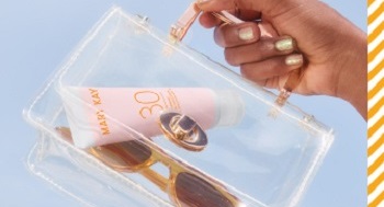 Foto van een model dat een transparant tasje met een tube van de Mary Kay® Minerale Zonverzorging SPF 30 en een zonnebril voor een blauwe achtergrond in haar hand houdt 