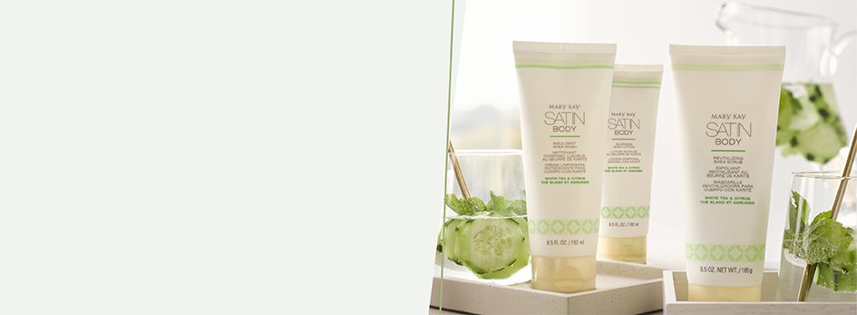 De Satin Body producten Satin Body® Indulgent Shea Wash White Tea & Citrus, Satin Body® Silkening Shea Lotion White Tea & Citrus en de Satin Body® Revitalizing Shea Scrub White Tea & Citrus staan op drie witte schalen.