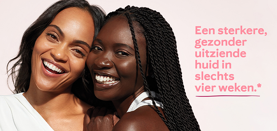 Twee vrouwen met een donkere huidskleur, dicht bij elkaar, lachend naar de camera, omringd door zonlicht en een lichtroze achtergrond.