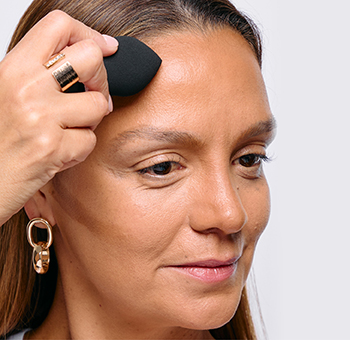 Een vrouw heeft verschillende tinten van de Mary Kay Multi-Benefit Concealer op verschillende delen van haar gezicht aangebracht en alles met een 