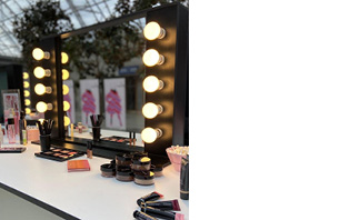 Verschillende Mary Kay make-up producten liggen op een kaptafel voor een verlichte make-up spiegel.