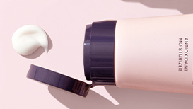 Geopende TimeWise® Antioxidant Moisturizer naast een centimeters groot likje van het product voor een lichtroze achtergrond