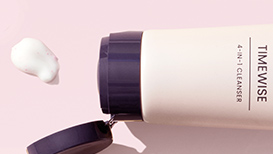 Geopende TimeWise® 4-In-1 Cleanser naast een centimeters groot likje van het product voor een lichtroze achtergrond