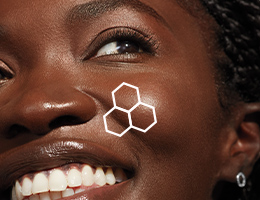 Close-up van een glimlachende donkere vrouw met bruine ogen een contour van het TimeWise® 3D complex op haar wang