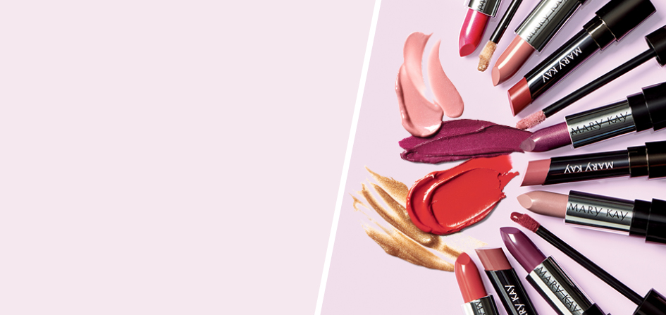 Diverse Mary Kay Hydrating Lipsticks, Semi Matte Lipsticks, Semi Shine Lipsticks en Ultimate Lipgloss liggen in een halve cirkel op een roze ondergrond – in het midden smudges van de producten.